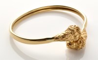 Lot 754 - A yellow metal bangle, the terminals decorated...