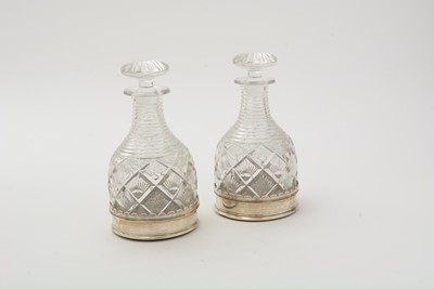 Lot 19 - A pair of George V silver wine coasters; together with a pair of cut glass decanters and stoppers