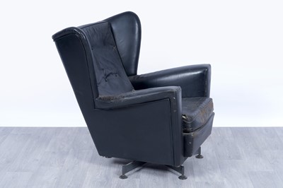 Lot 64 - A 1950’s black leather wingback revolving armchair