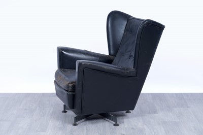 Lot 64 - A 1950’s black leather wingback revolving armchair