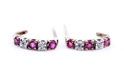 Lot 242 - A pair of ruby and diamond half hoop earrings