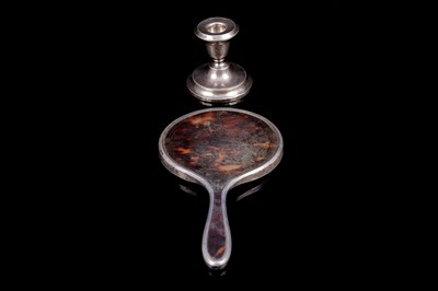 Lot 199 - A 1920s silver mounted tortoiseshell hand mirror; and a candlestick holder